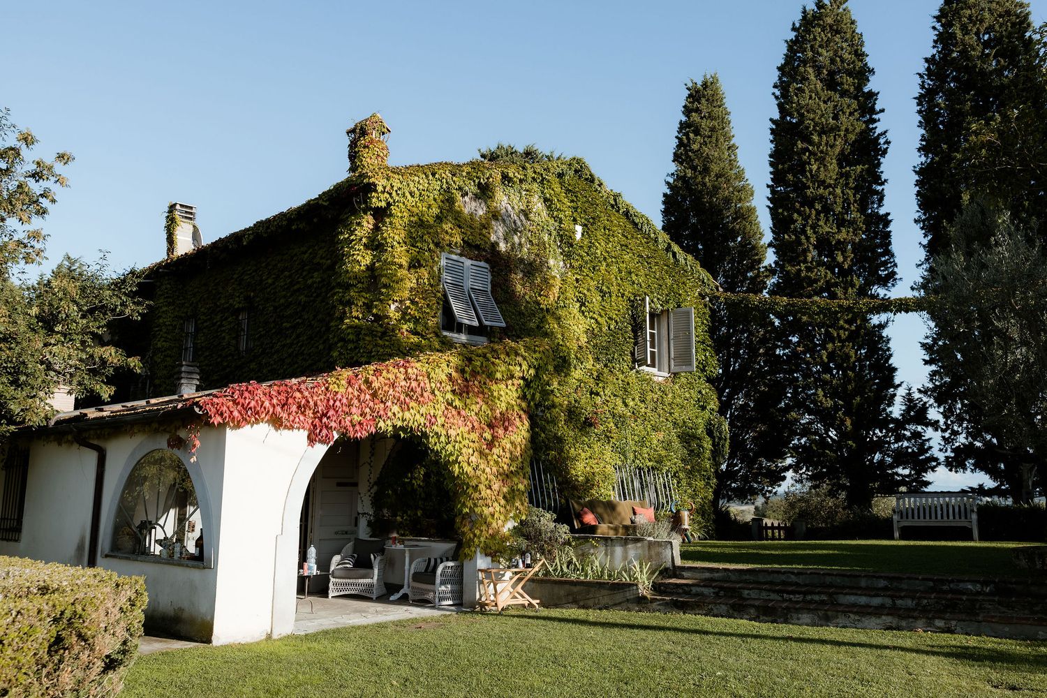 A scenic panoramic view of a Mediterranean villa with cypress trees and lush gardens in the countryside.