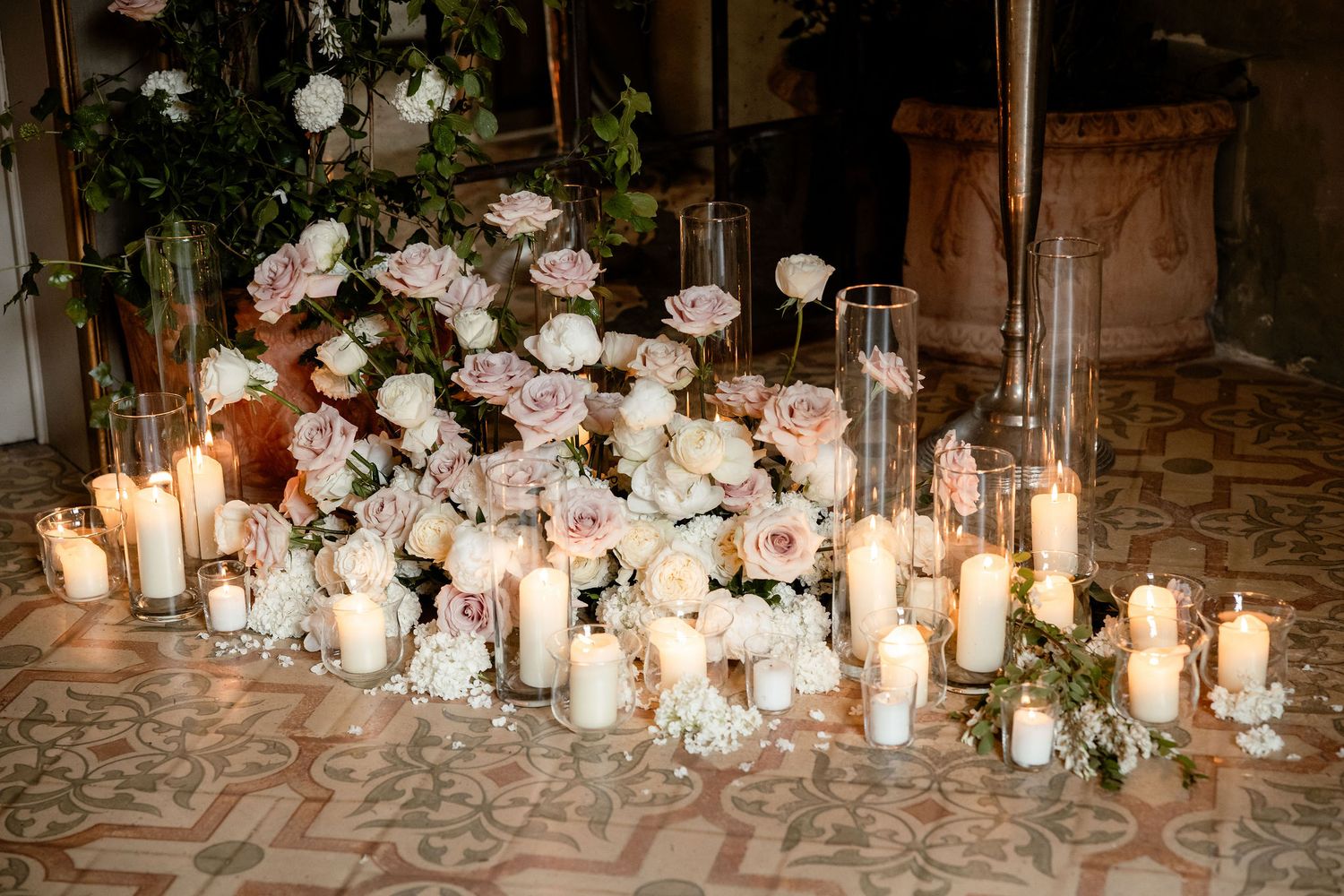 Elegant wedding tablescape with crystal candle holders, white roses, and glowing tealights arranged on a gold tablecloth.