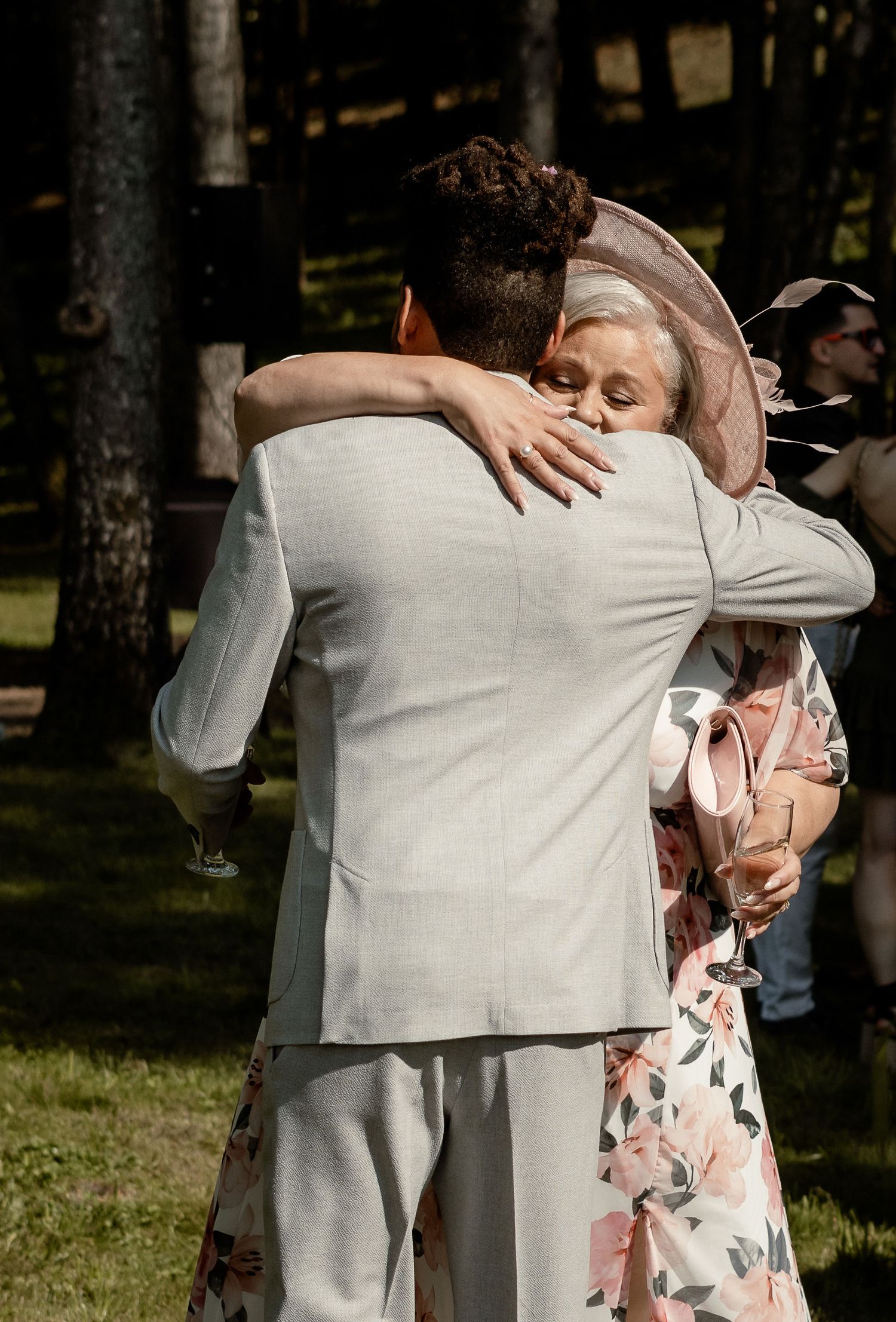 Emotional wedding embrace captured in warm sunlit forest setting.
