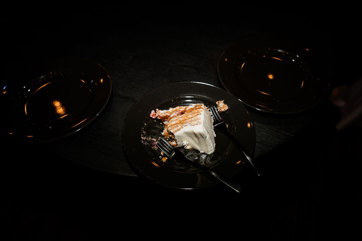 Dramatic low-light photo of wedding cake slices on dark plates.