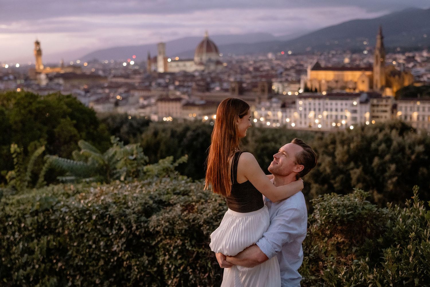 A romantic embrace overlooking the stunning cityscape of Florence, Italy with the Duomo cathedral visible at sunset.