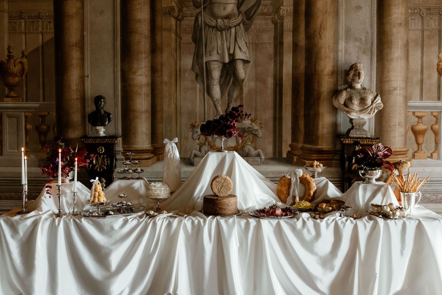 Long banquet table set with white linens and elegant place settings in a grand historic dining hall.
