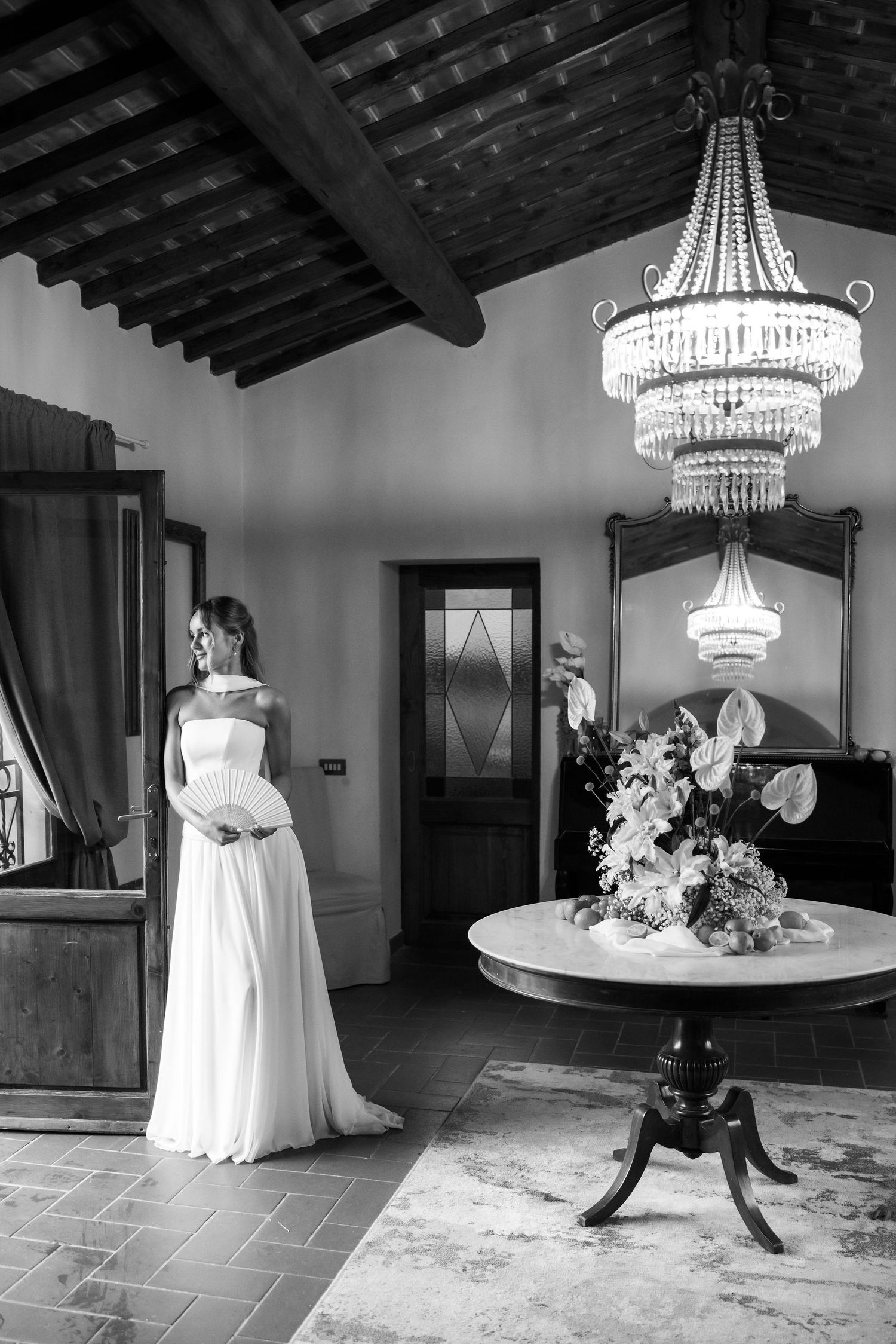 A black and white photo series showing elegant chandeliers and wedding dress details in a rustic venue interior.