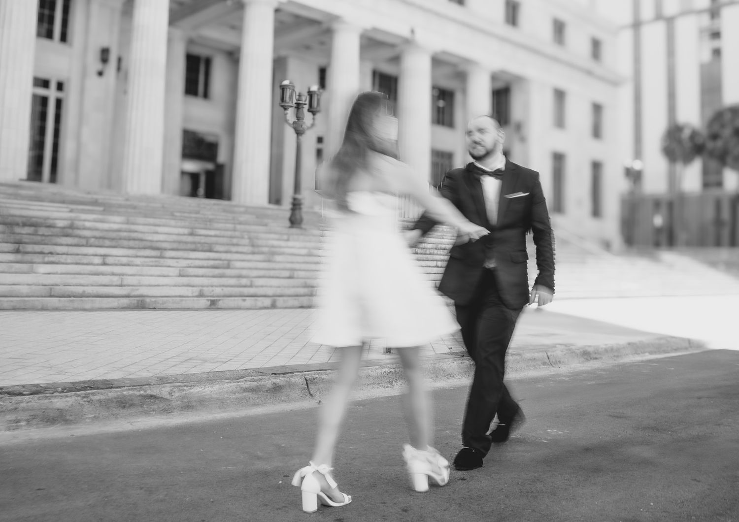 Black and white motion photo of a couple dancing on steps of a historic building.