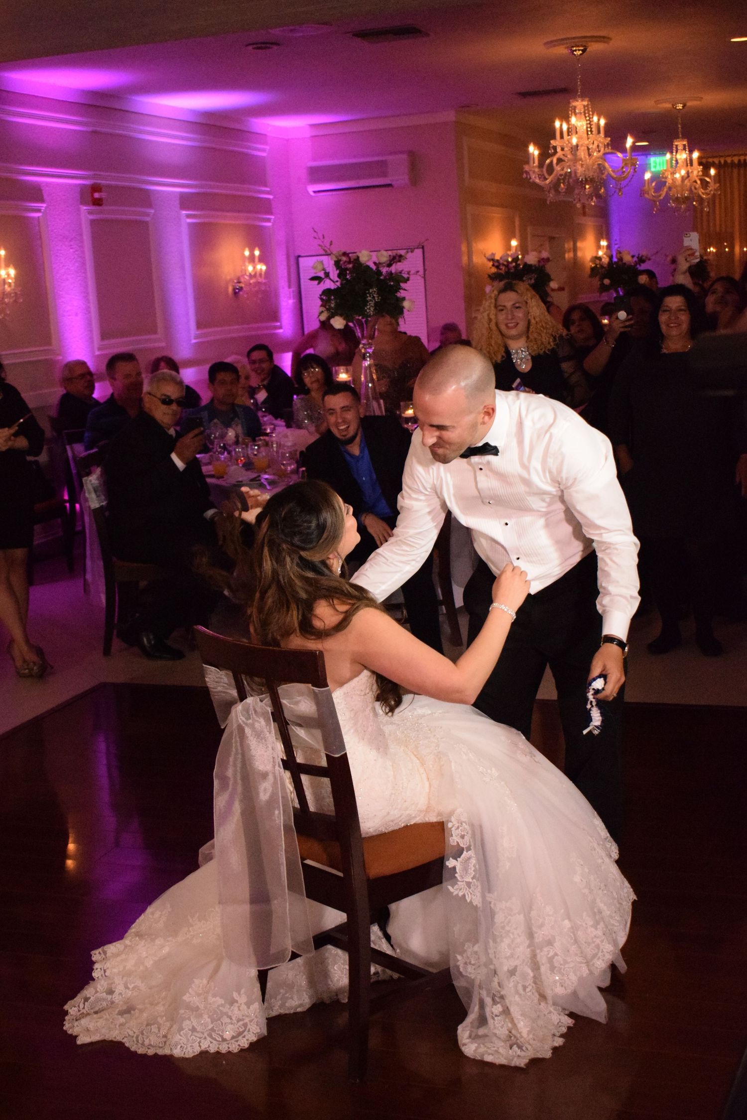 Couple shares romantic dance moment at wedding reception with purple uplighting.