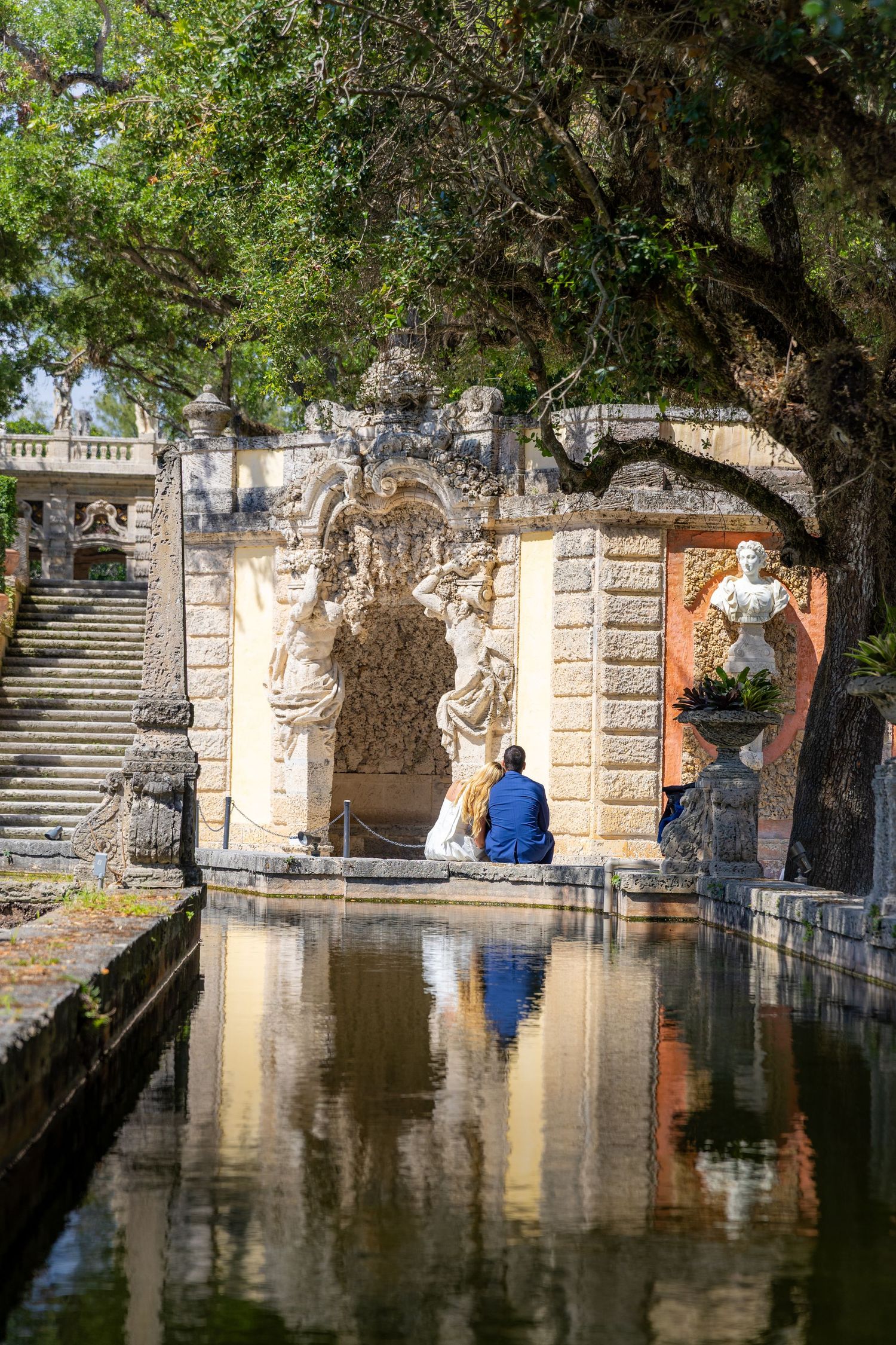 Someone sits peacefully by an ornate fountain pool at Vizcaya Museum and Gardens in Miami, reflecting in the still water.