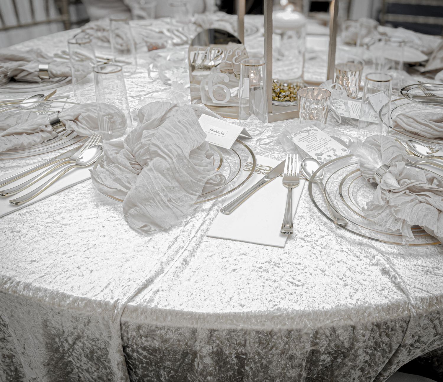 Elegant wedding reception table setting with crystal glasses and white tablecloth.