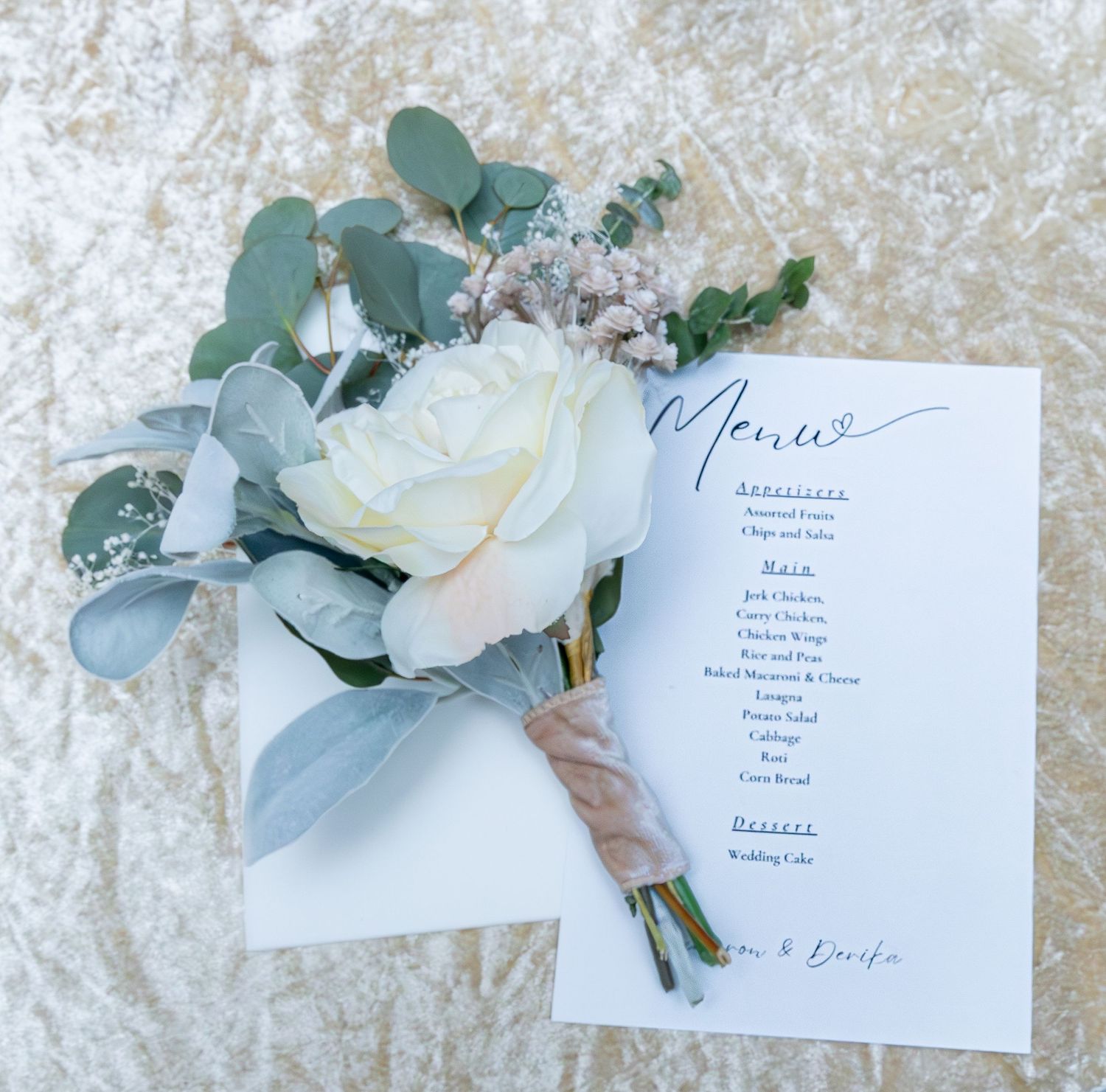 Yellow rose wedding bouquet with eucalyptus leaves alongside an elegant menu card on a lace background.