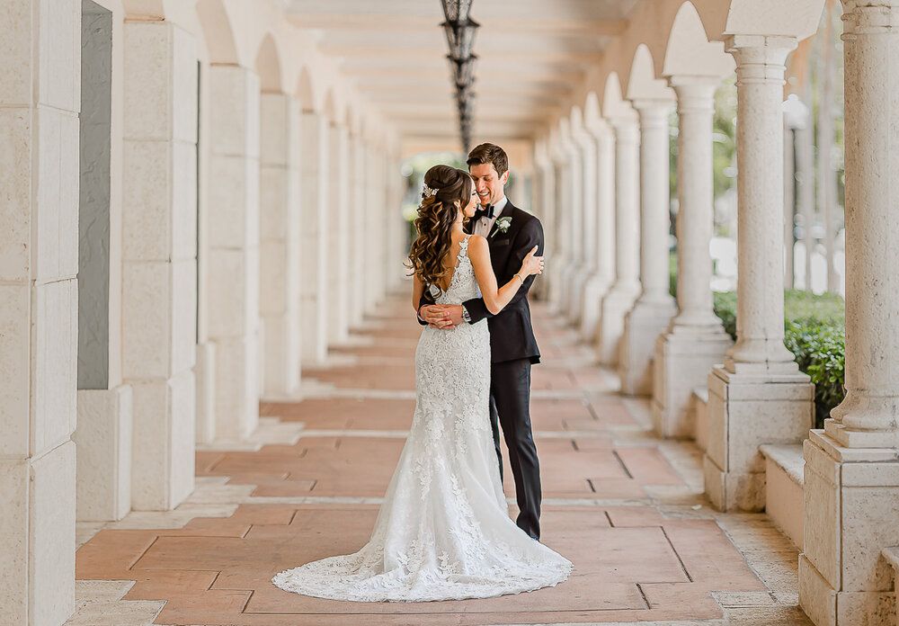 Beautiful wedding portrait taken in a corridor with white columns creating dramatic perspective.