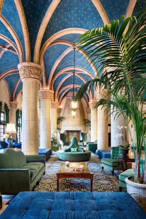 Gothic-style lounge with vaulted blue ceiling, ornate columns, and tropical plants decorating the elegant space.
