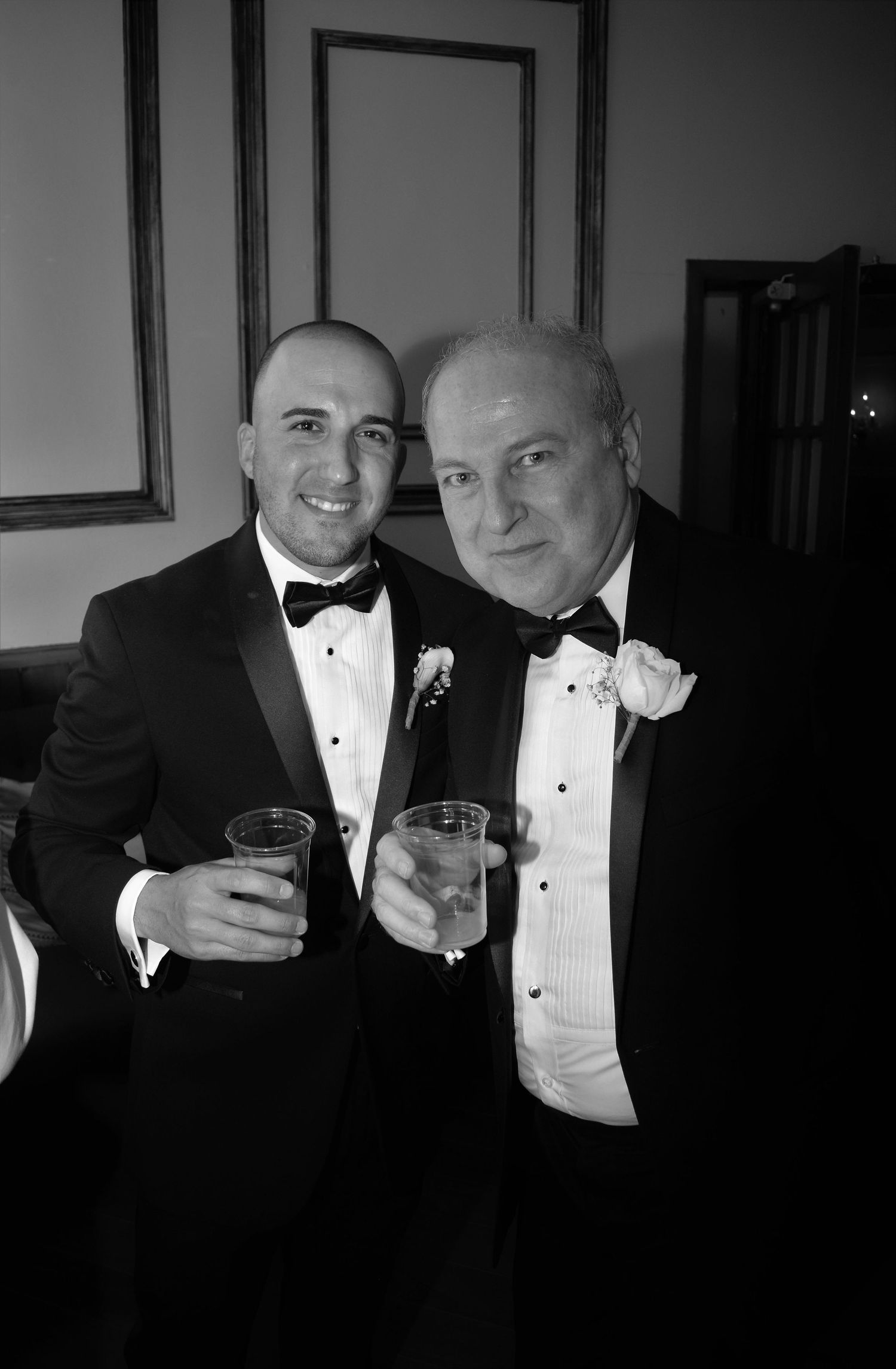 Two men in tuxedos holding champagne glasses at formal event.