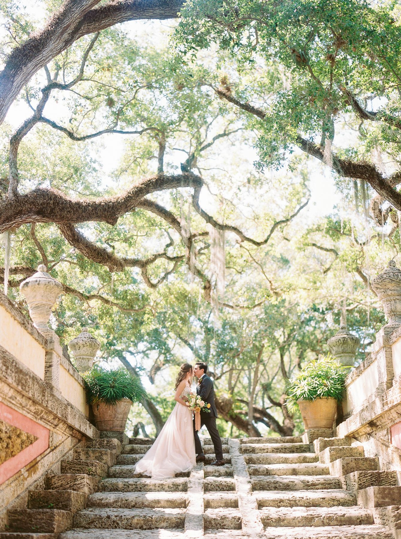 Romantic wedding couple embracing under grand archway with classic columns.