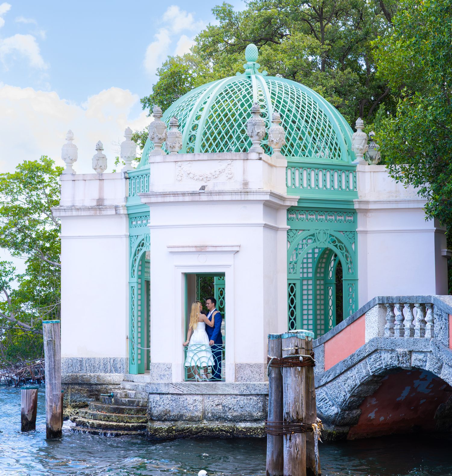 Ornate turquoise and white stone gazebo pavilion with latticed dome overlooking the waterfront in Vizcaya Gardens, Miami.