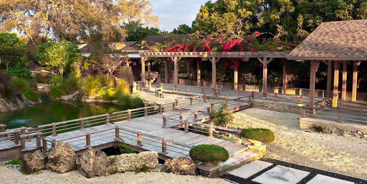 Traditional Japanese garden featuring a wooden pavilion and stone bridge over a tranquil pond.