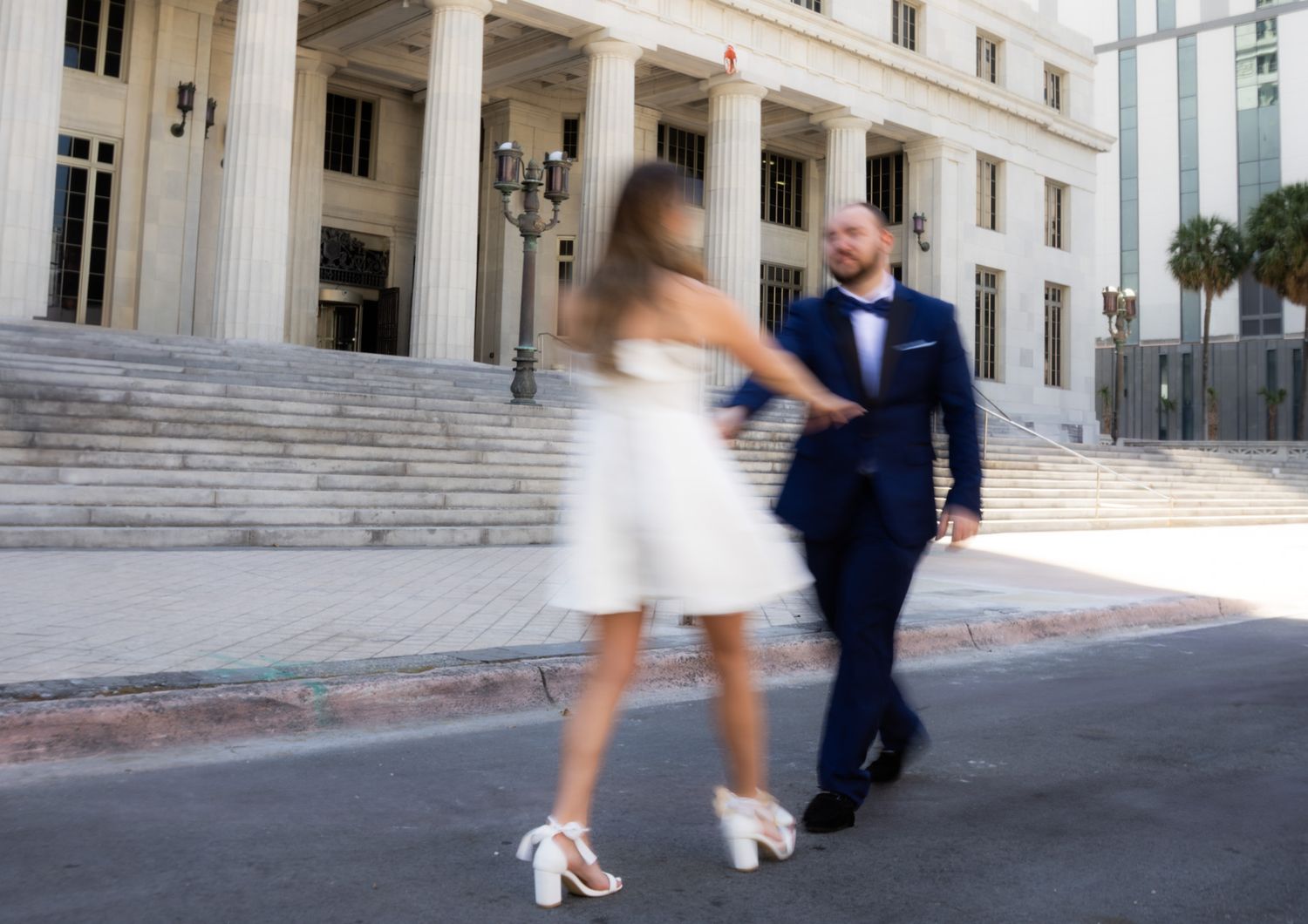 Motion blur photo of a couple dancing outside a classical building with columns.