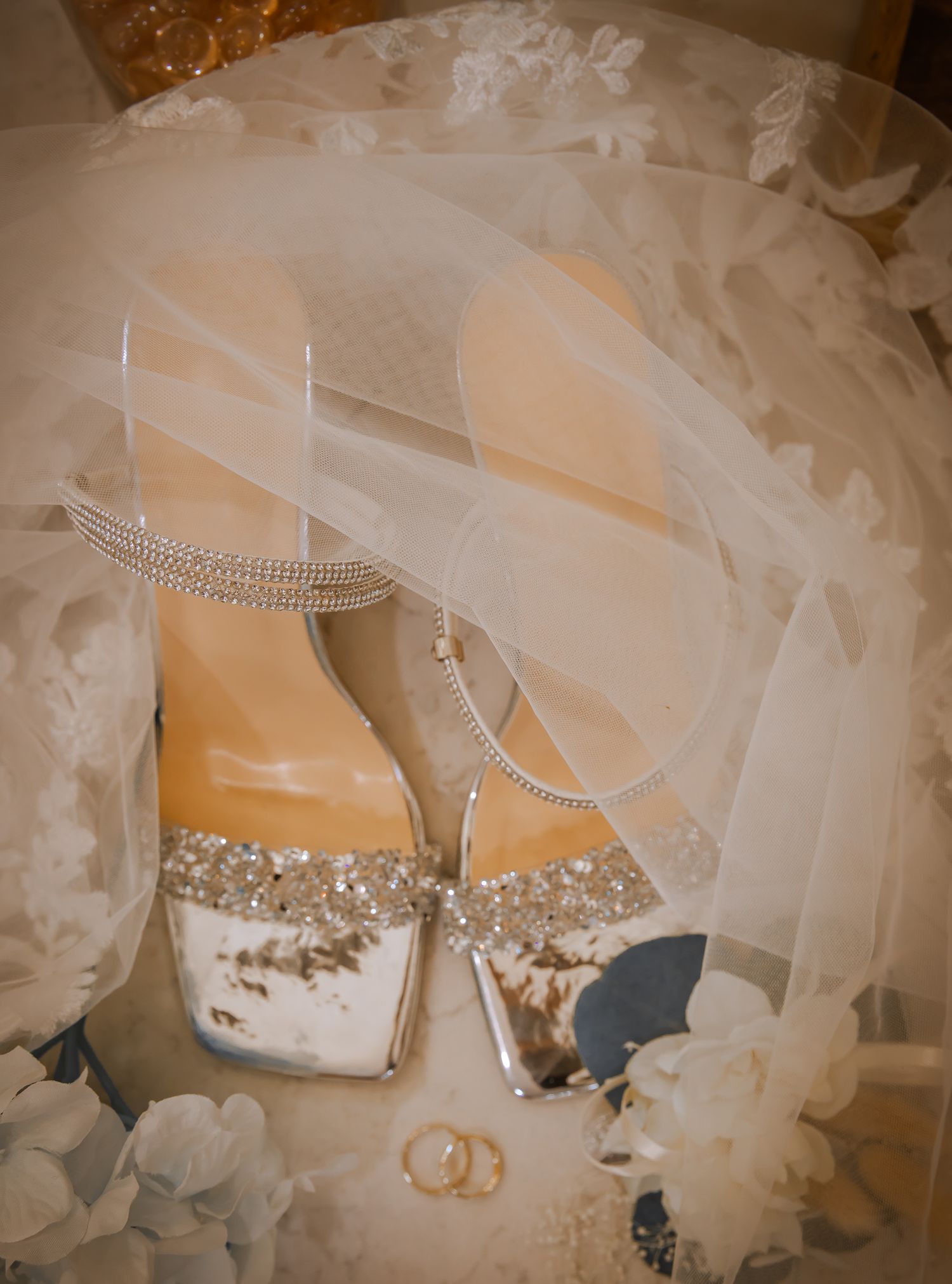Crystal-embellished bridal shoes with wedding rings and veil.