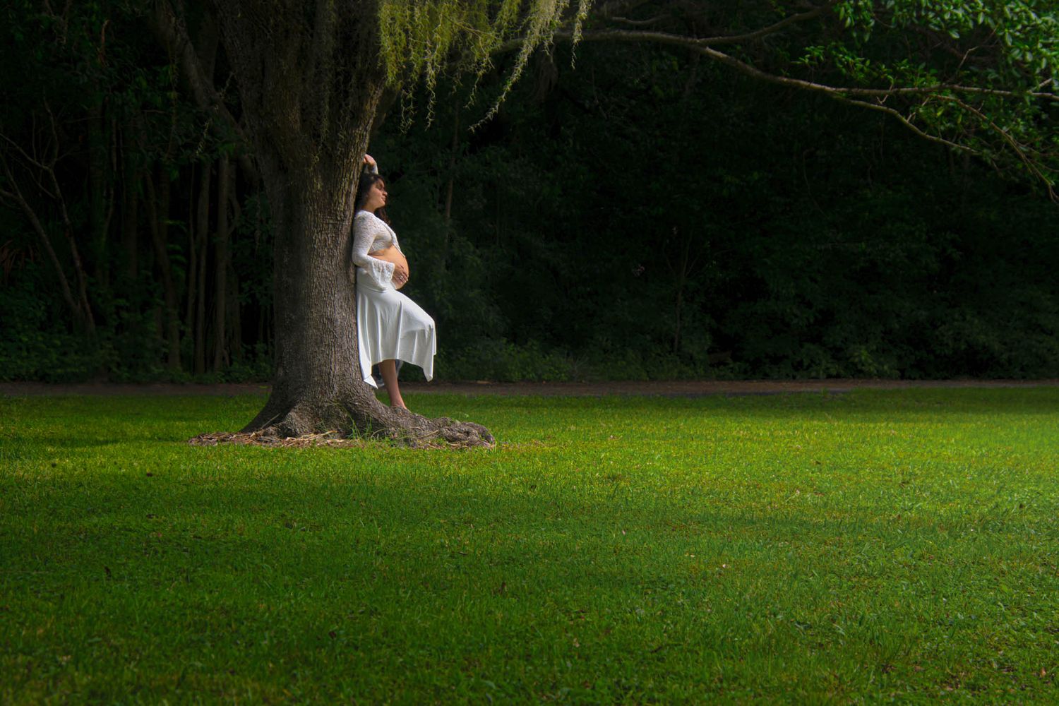 Ethereal outdoor portrait against a backdrop of lush green trees.