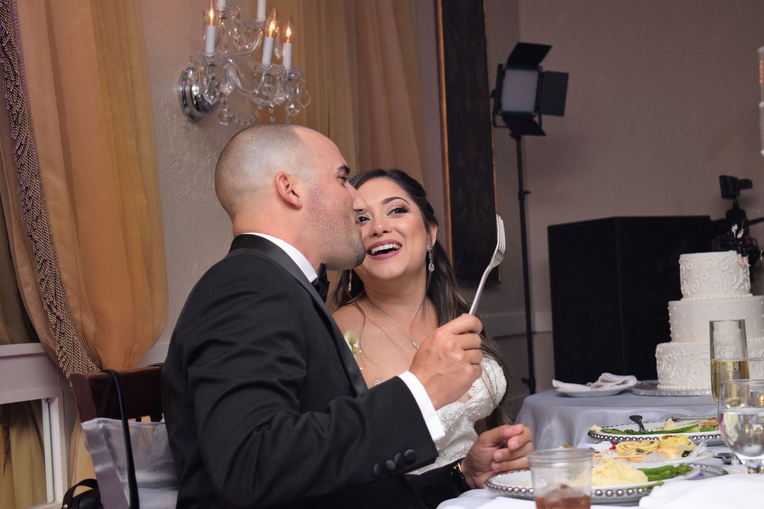 Candid reception moment of newlyweds laughing together while dining.