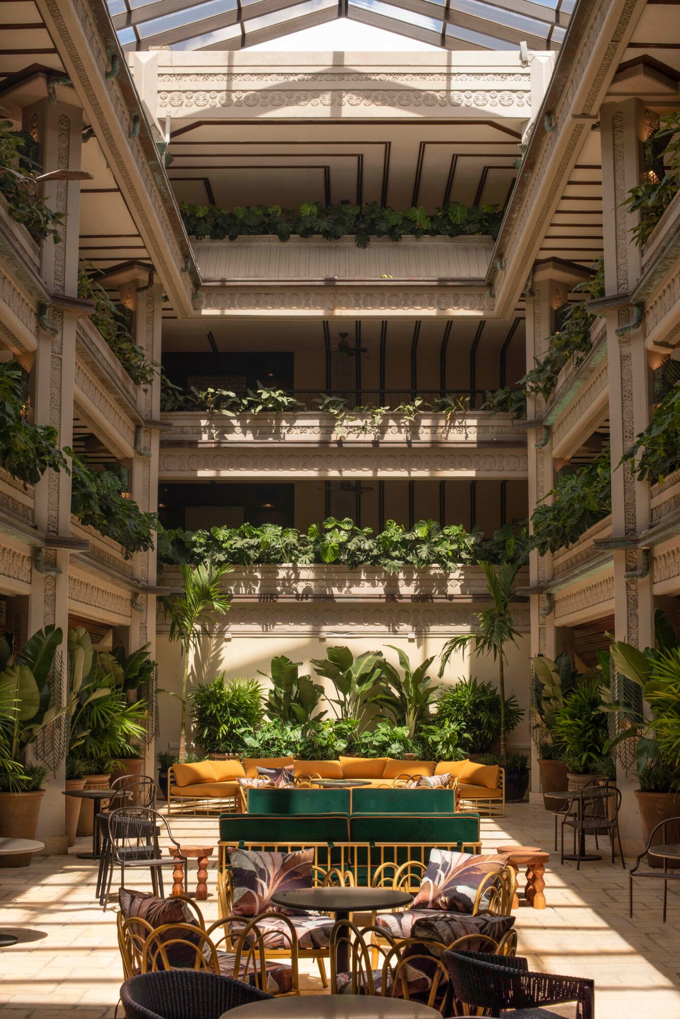 Luxurious atrium lounge with multi-level indoor garden terraces, plush seating, and natural light streaming through a glass ceiling.