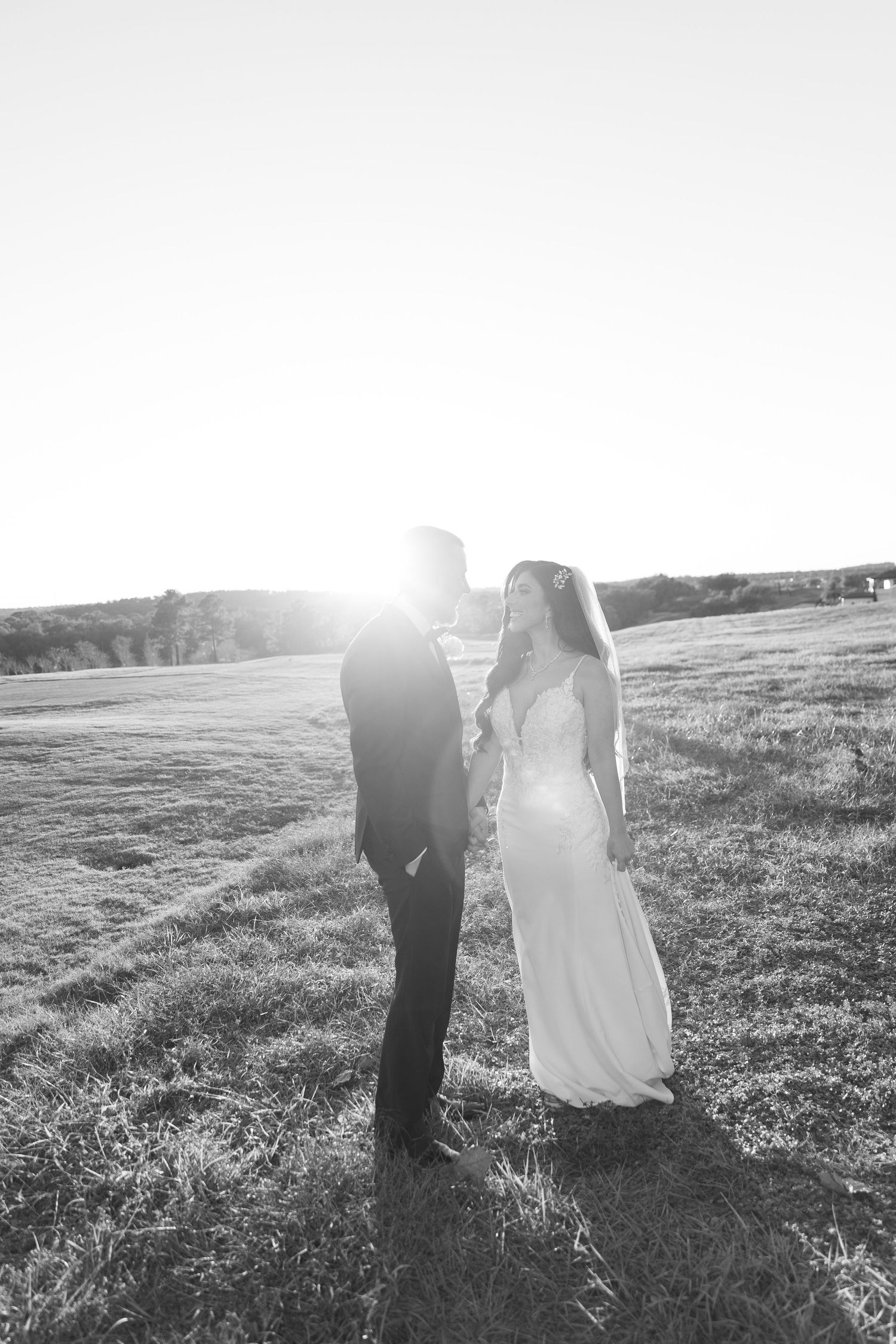 Black and white silhouette of newlyweds in an open field during golden hour.