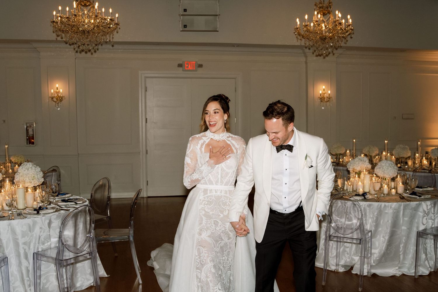 Elegant reception hall with crystal chandeliers and white table settings.