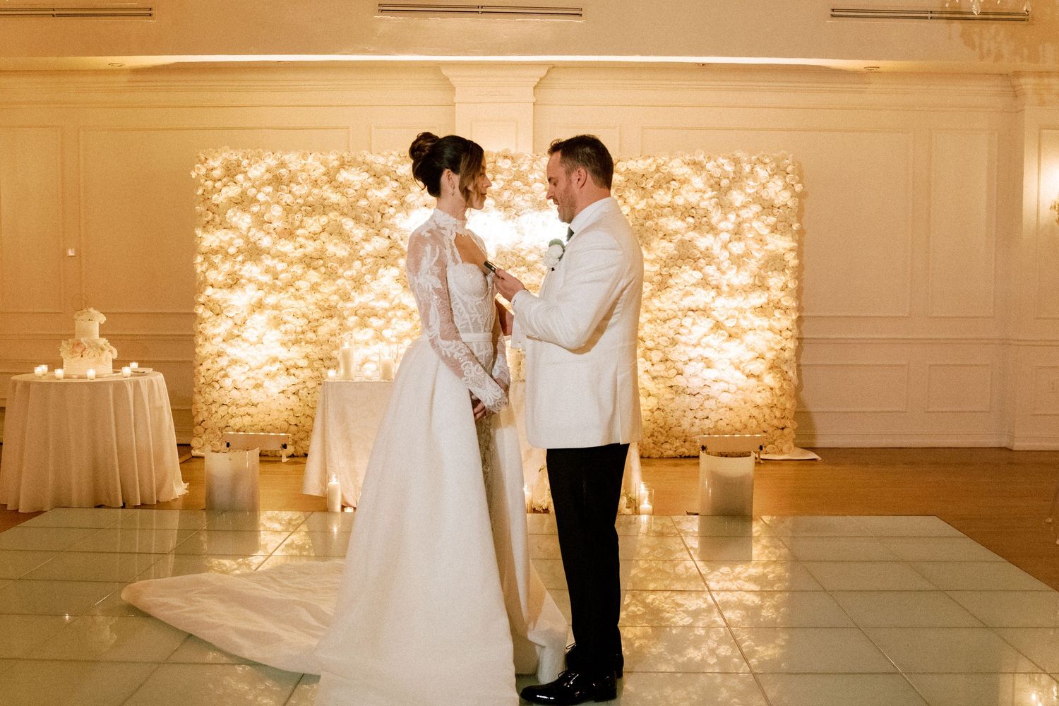 Romantic first dance moment in front of an illuminated floral backdrop at a wedding reception.