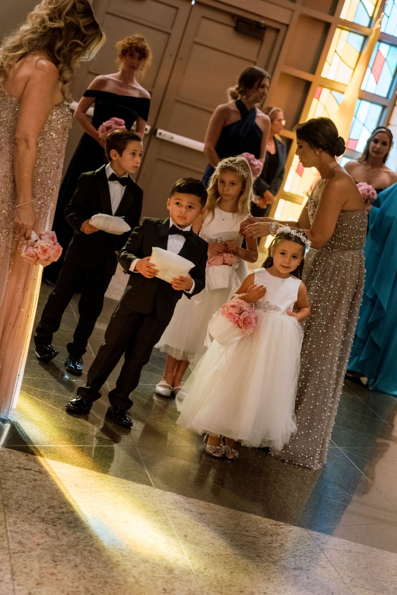 Young children in formal attire gather on a dance floor at a wedding reception.