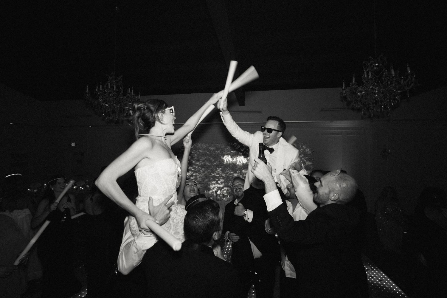 Wedding party dancing energetically under black and white lighting effects.