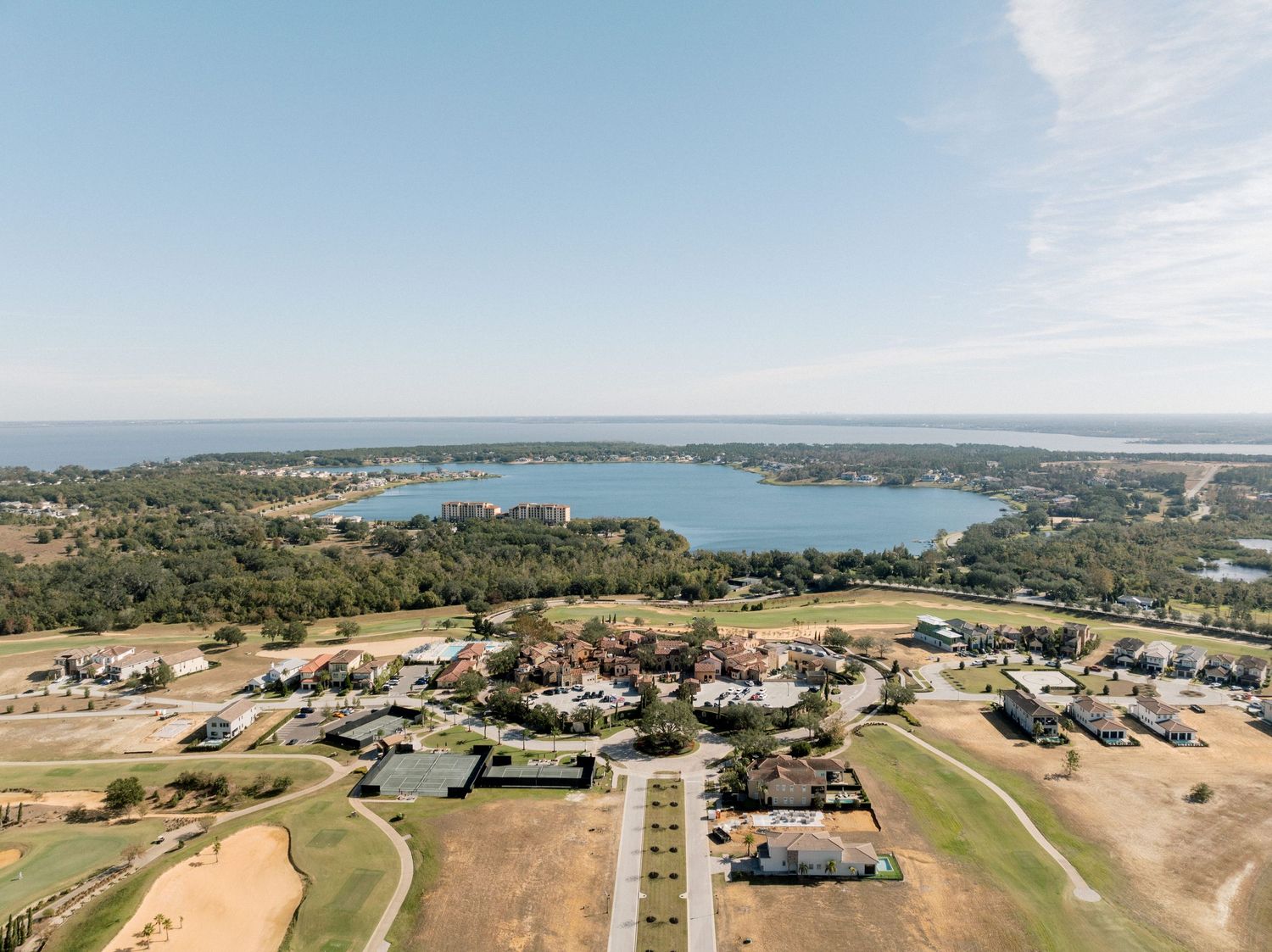 Aerial view of a lakeside community with homes and winding roads surrounded by water and rural landscape.