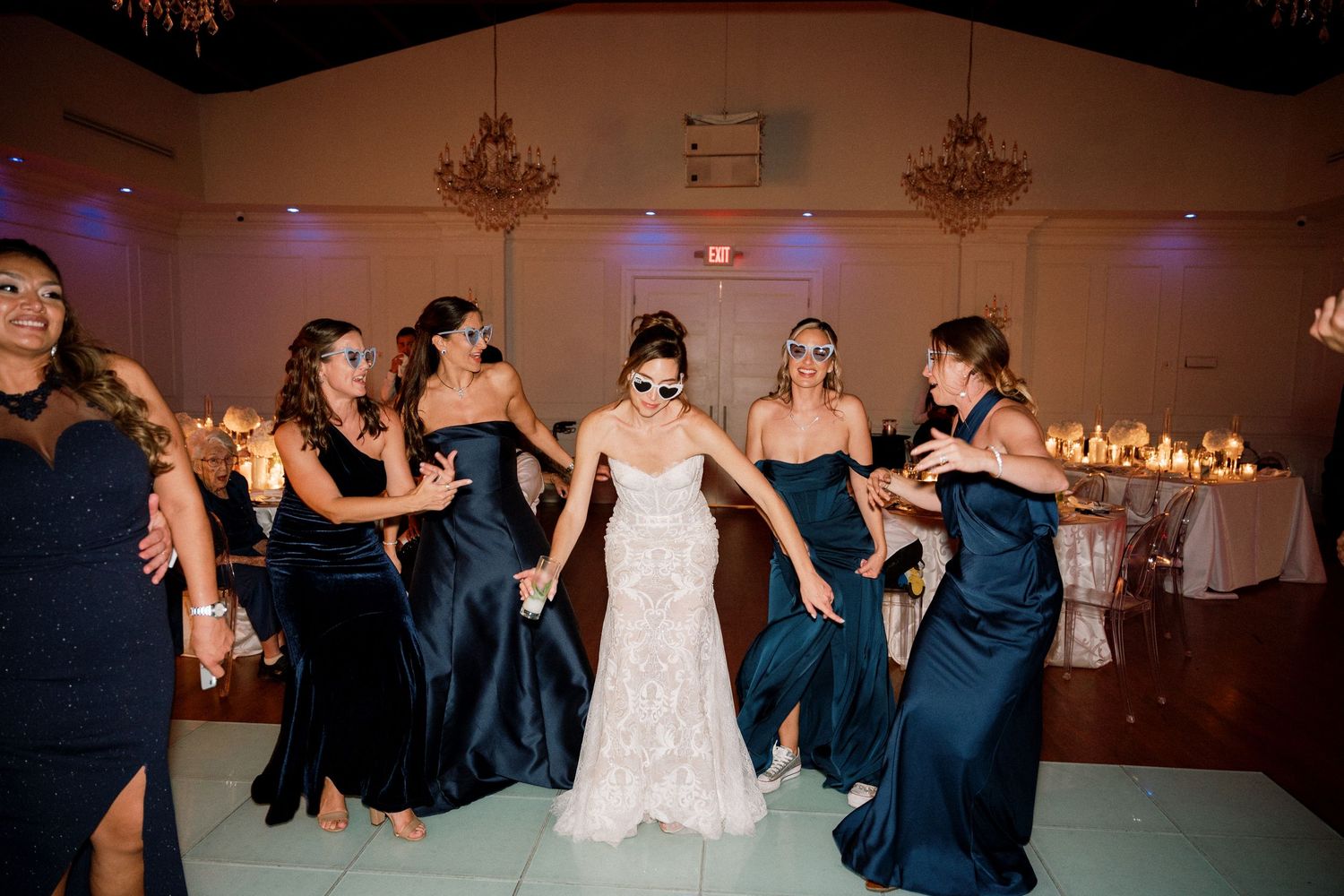 Wedding reception dance floor filled with guests dancing under warm lighting.