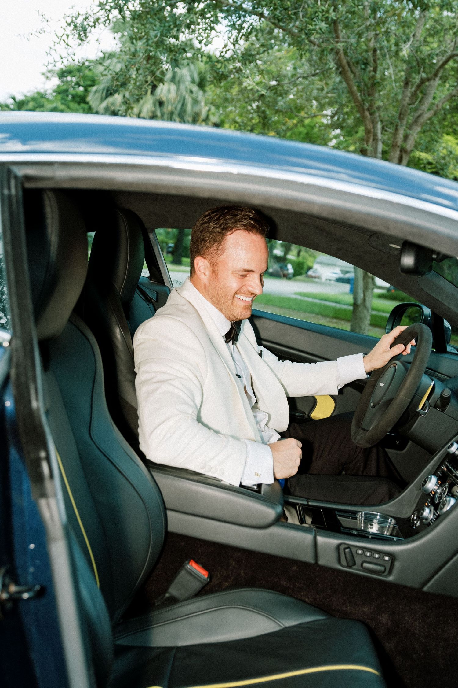 Person in formal attire demonstrating various driving positions and adjustments inside a modern vehicle interior.
