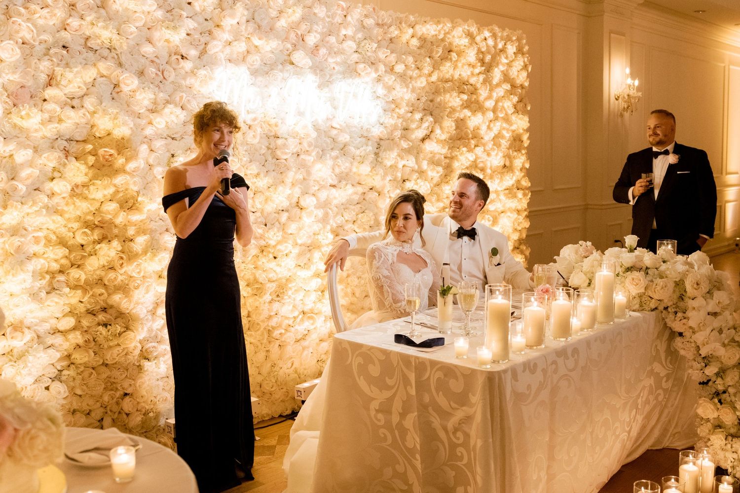 Wedding reception space decorated with illuminated floral walls and elegant lighting.