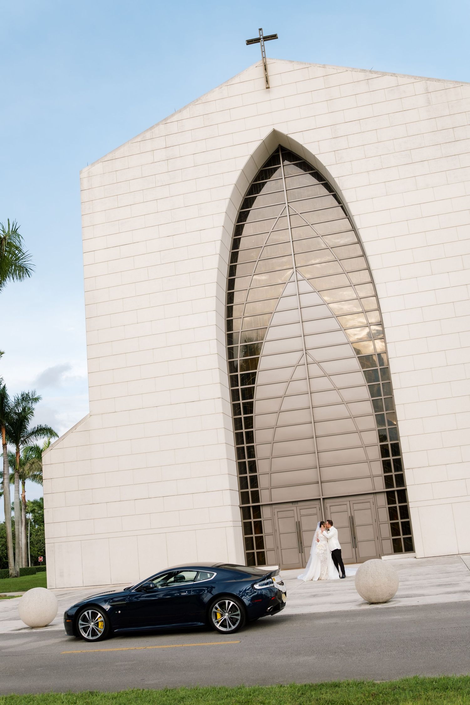 Modern white architectural structure with arched openings and a sleek black sports car parked in front.