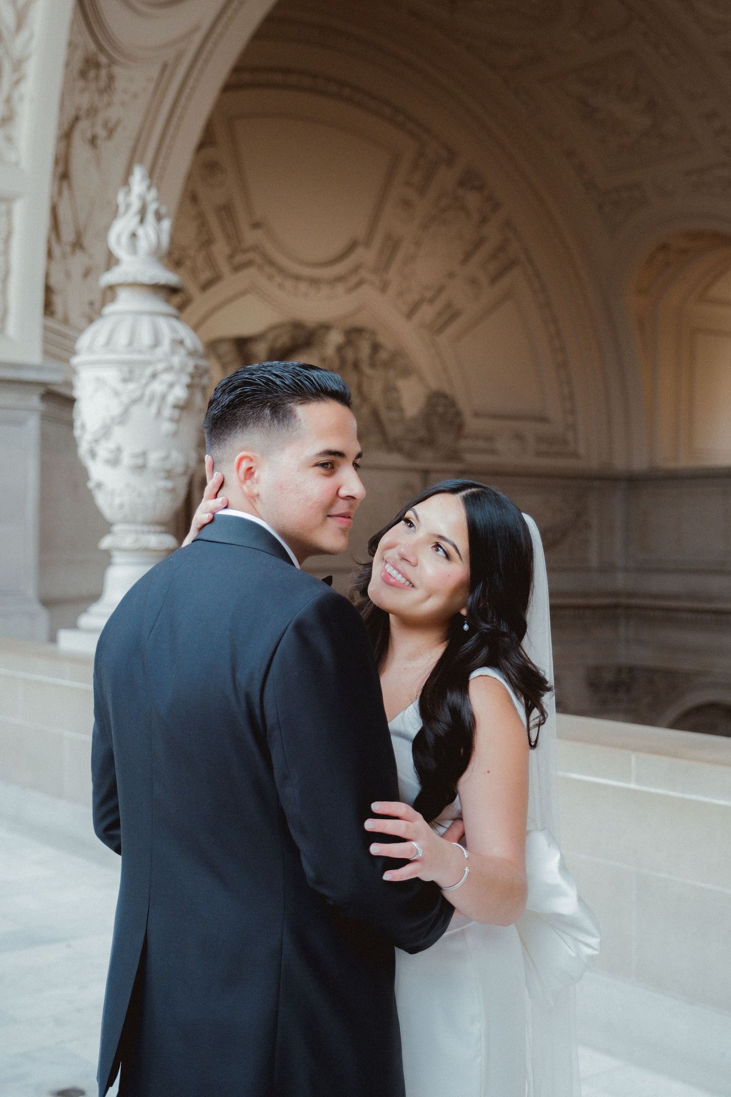 A romantic couple in formal attire share intimate moments in an ornate architectural setting.