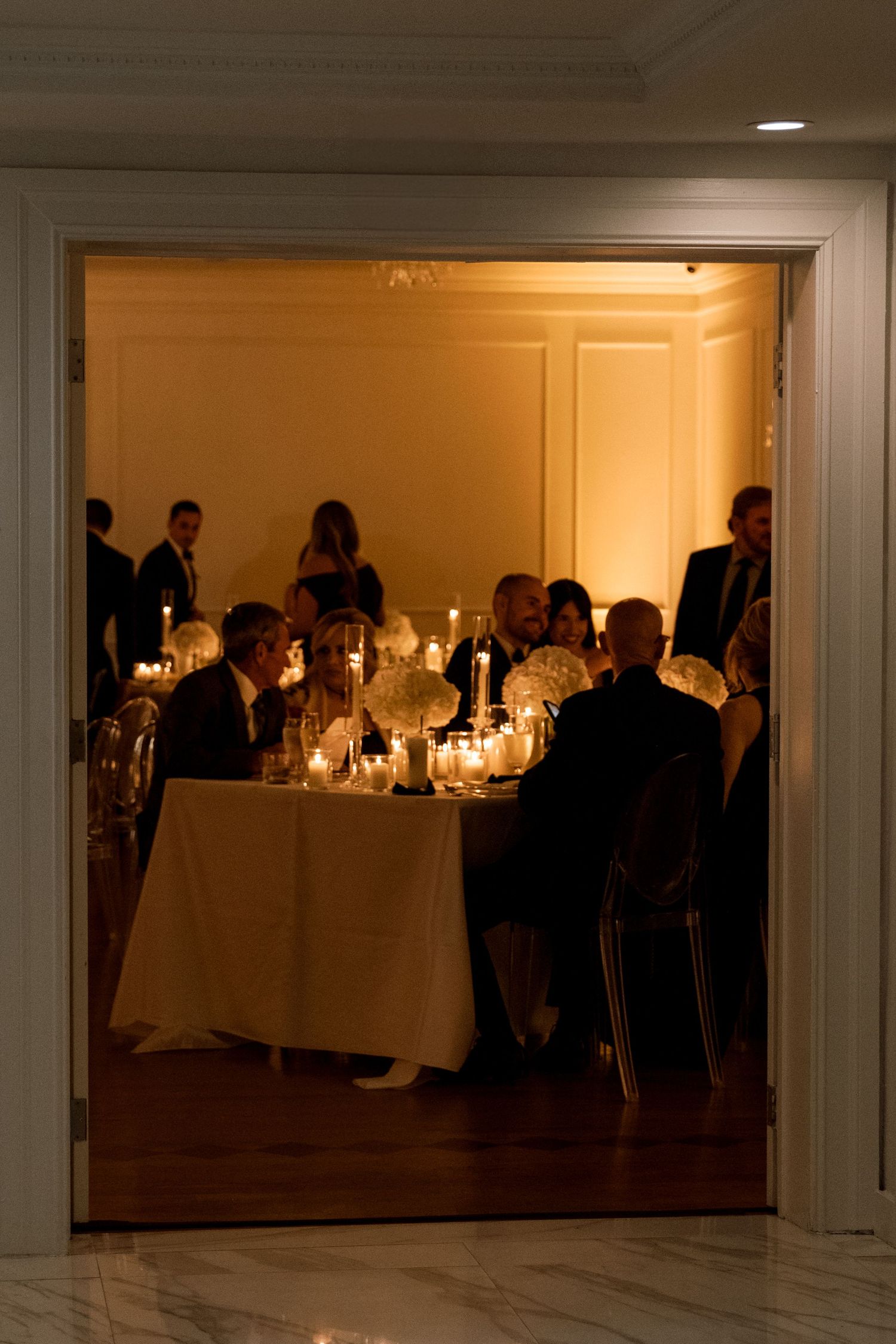 Candlelit wedding reception tables set in a dimly lit banquet hall with elegant place settings.
