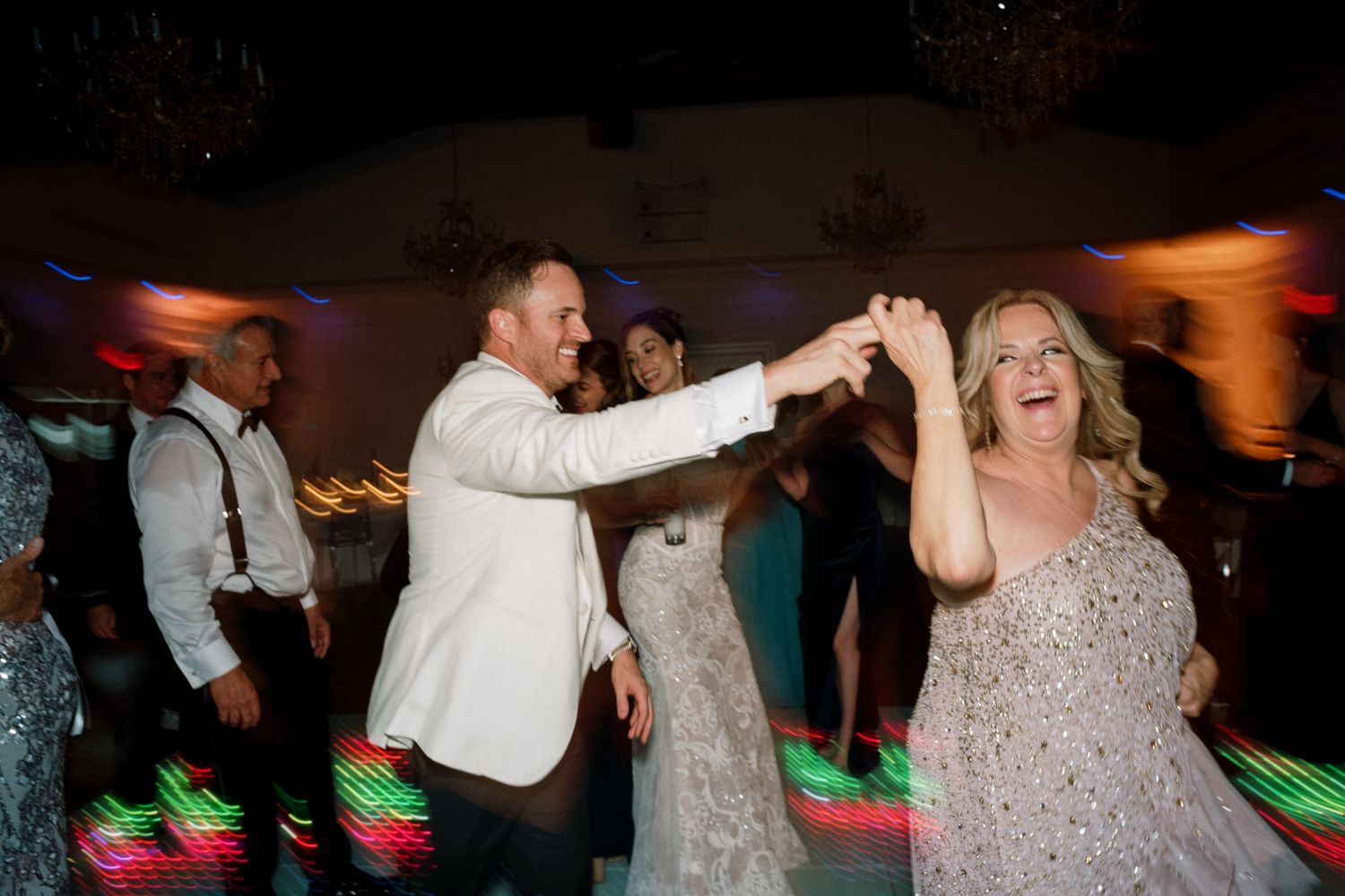 Energetic dancing and celebration at a wedding reception with festive lighting.