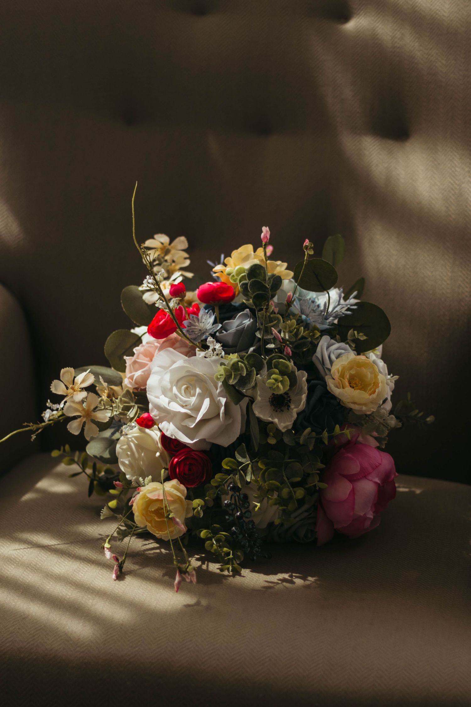 Moody still life of roses and mixed flowers laying on dark surface with dramatic lighting in Greenville, South Carolina.