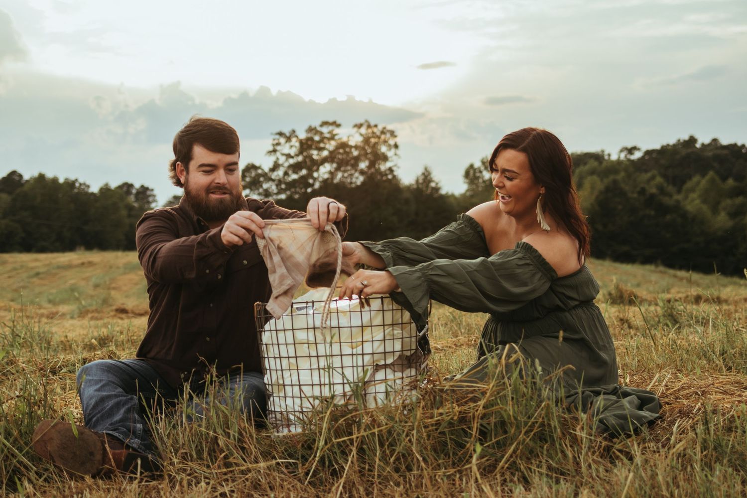 A couple playfully interacting with a basket between them in a golden meadow in Toccoa, GA.