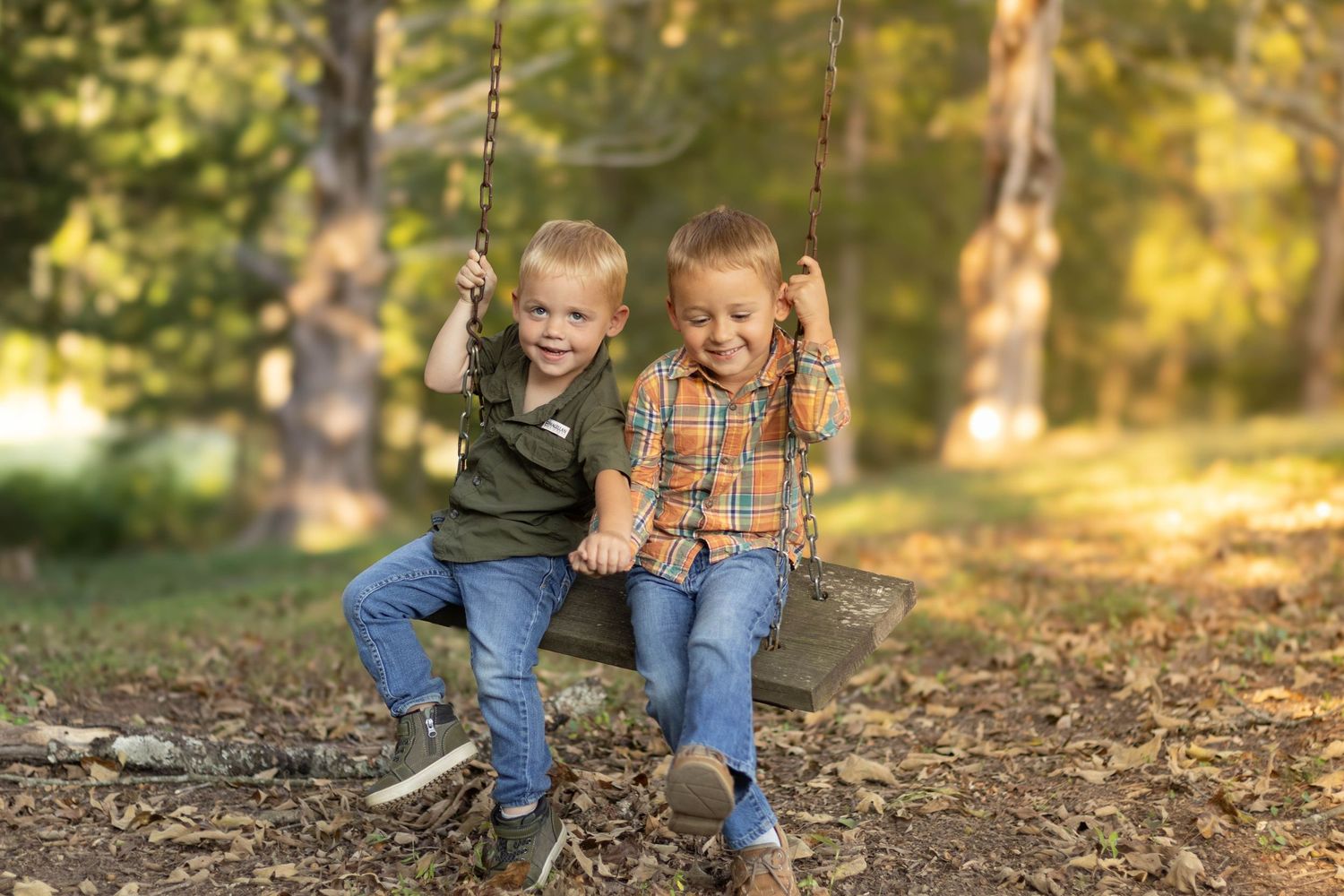 Children playing together on fallen leaves in a sunlit autumn setting at Geary Farm in Toccoa, GA.
