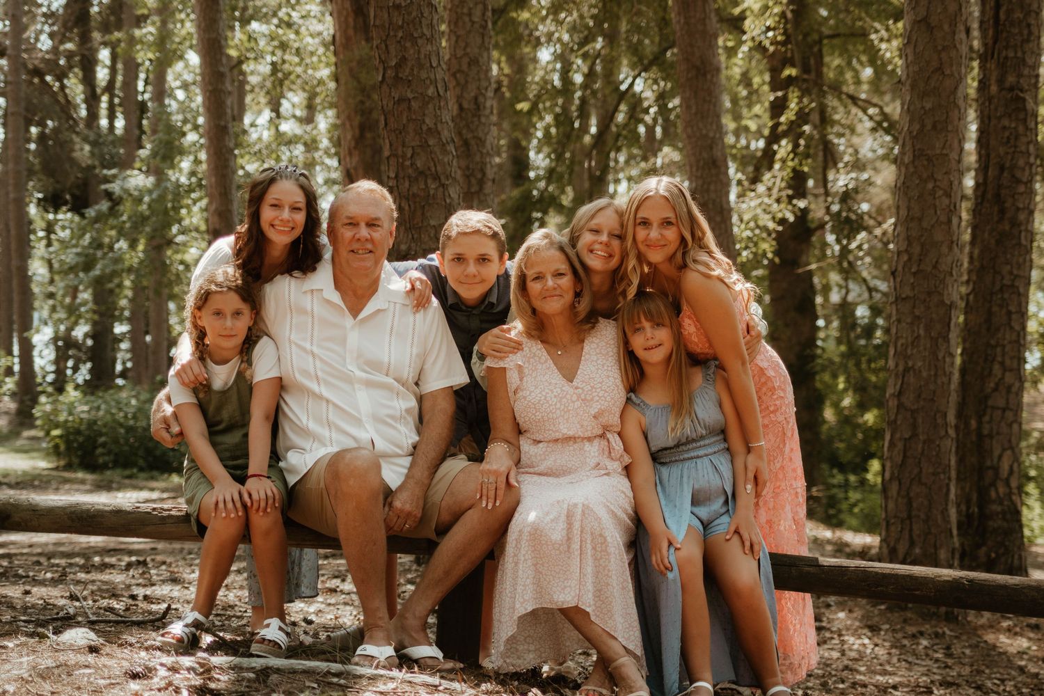Family seated together on wooden steps in a sunlit forest setting at Tugaloo State Park near Lake Hartwell.