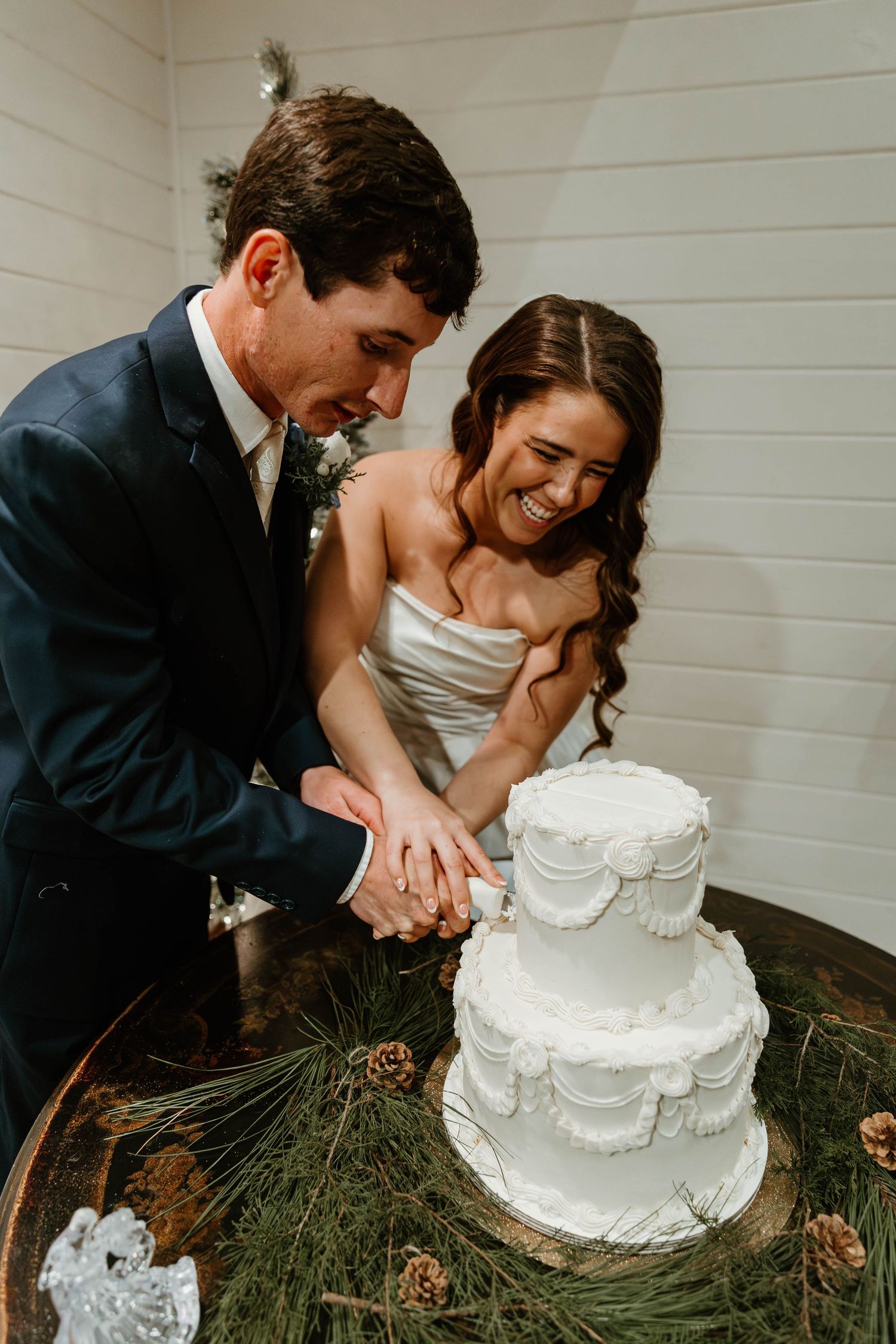 A romantic wedding cake cutting sequence shows a couple playfully feeding each other cake in front of white walls.