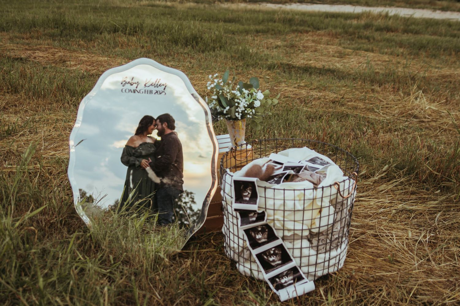 A decorative mirror and basket with ultrasound photos displayed in a rustic outdoor setting for a pregnancy announcement photo in Toccoa.