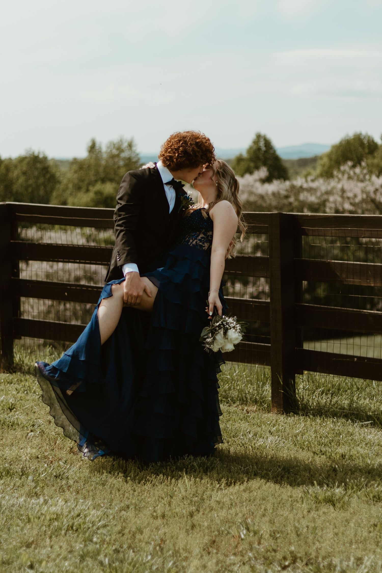 A romantic dip pose against a rustic fence with a blue formal gown in Northeast GA.