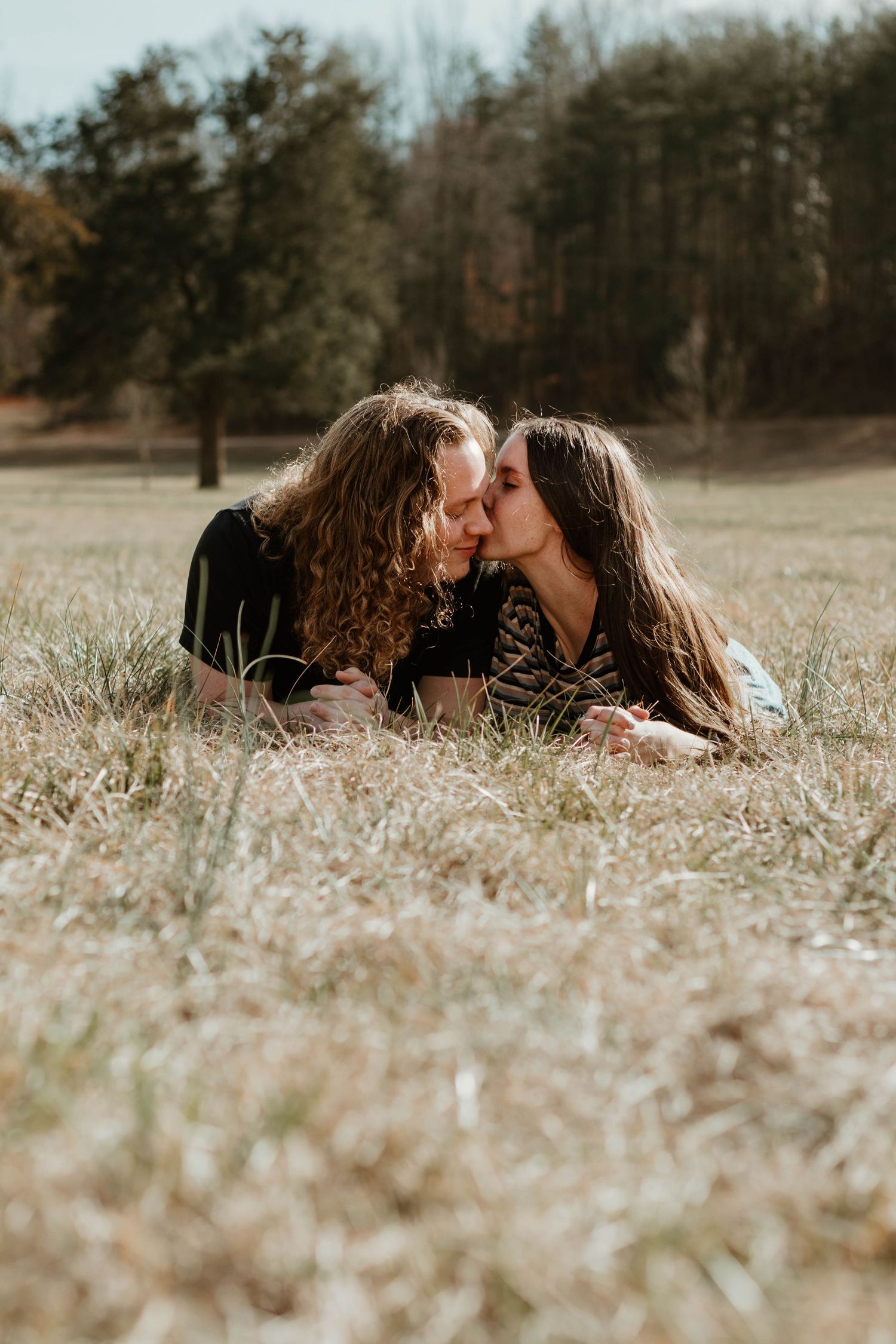 Couple sharing intimate moment while lying in dry grass field at Geary Farm in Toccoa, GA.