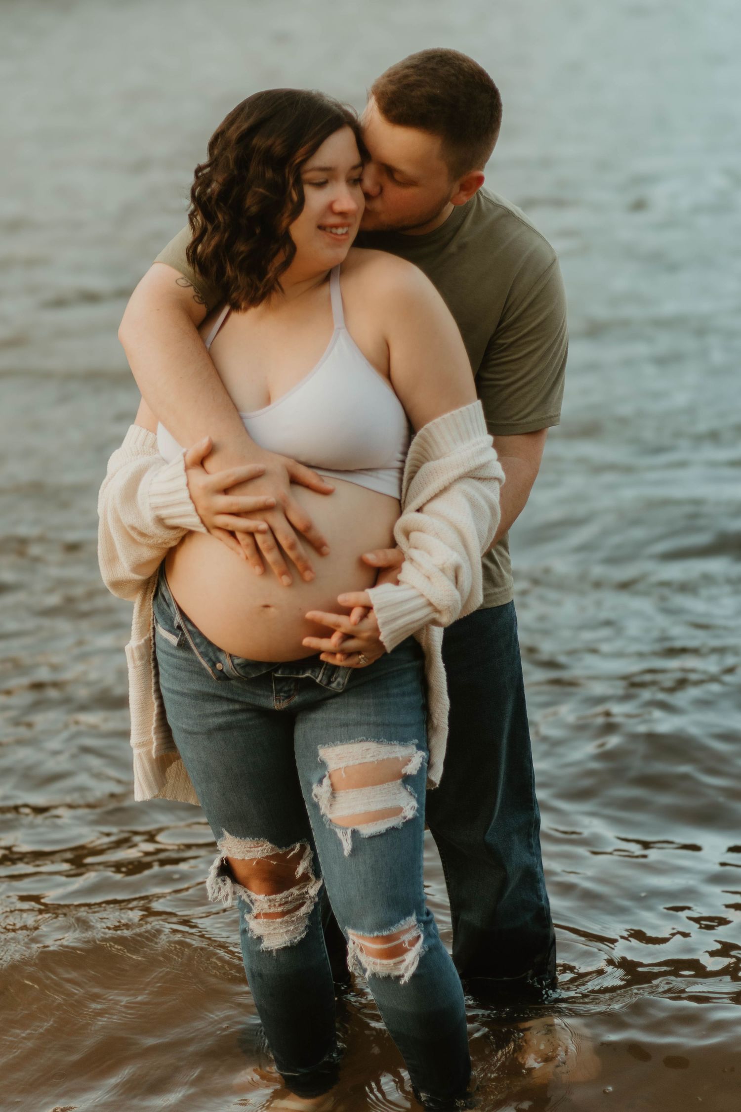 Intimate lakeside maternity photo with couple standing in water wearing casual attire in Lake Hartwell.