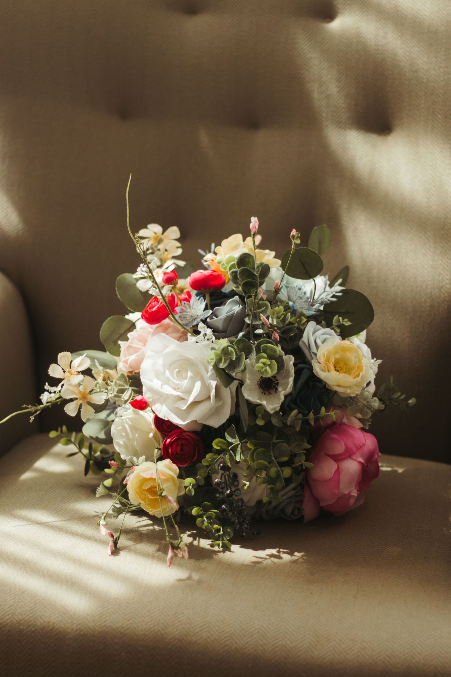 A romantic flower arrangement with white roses, red accents, and greenery casting soft shadows in sunlight in Greenville, South Carolina.