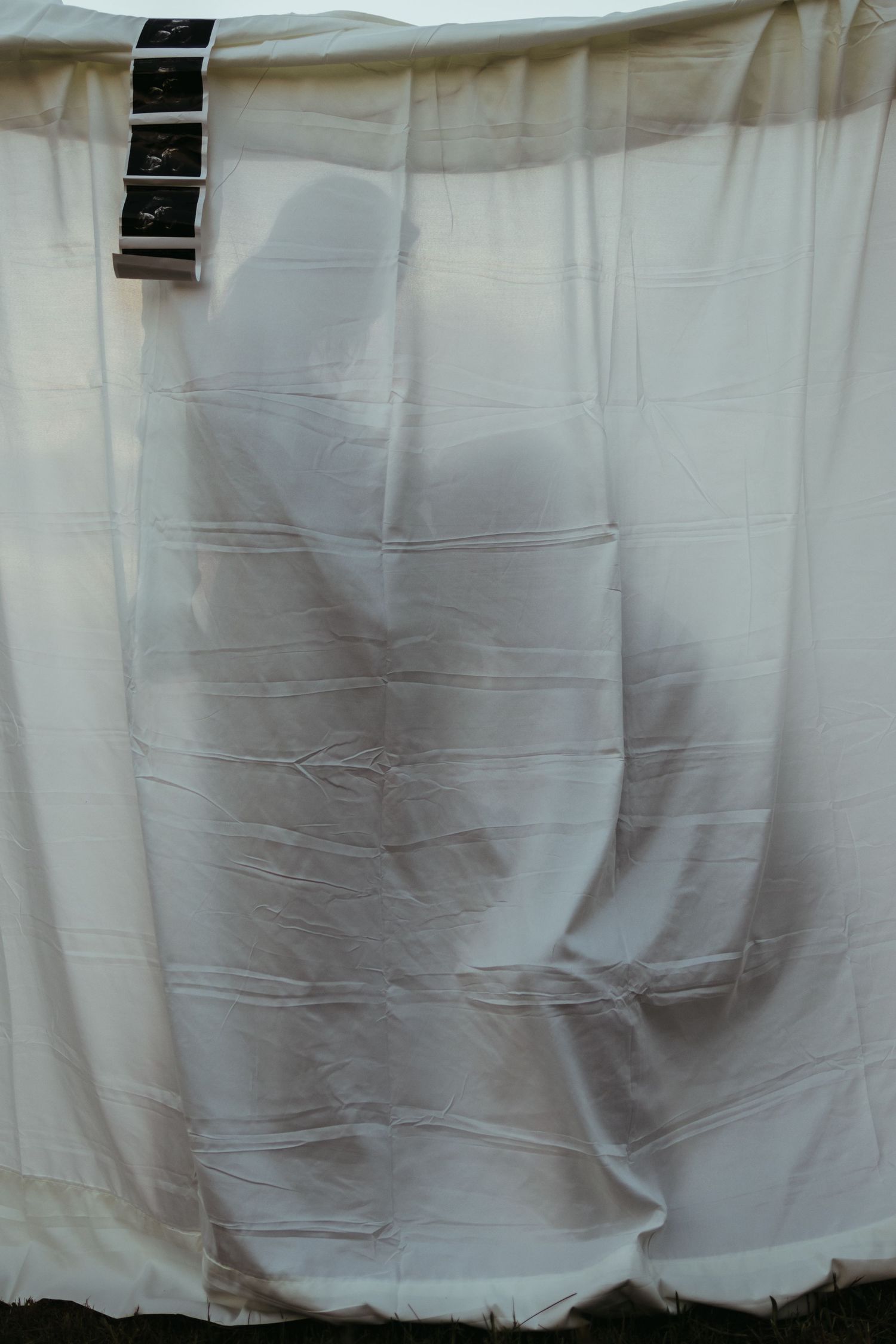 Black and white film strips hanging against a white fabric backdrop for a creative maternity photo in northeast Georgia.