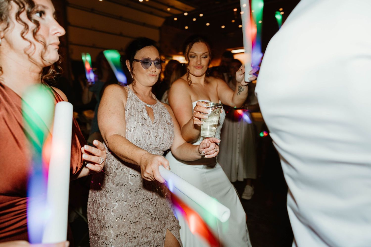 Wedding reception dance floor filled with colorful lights and celebrating guests.