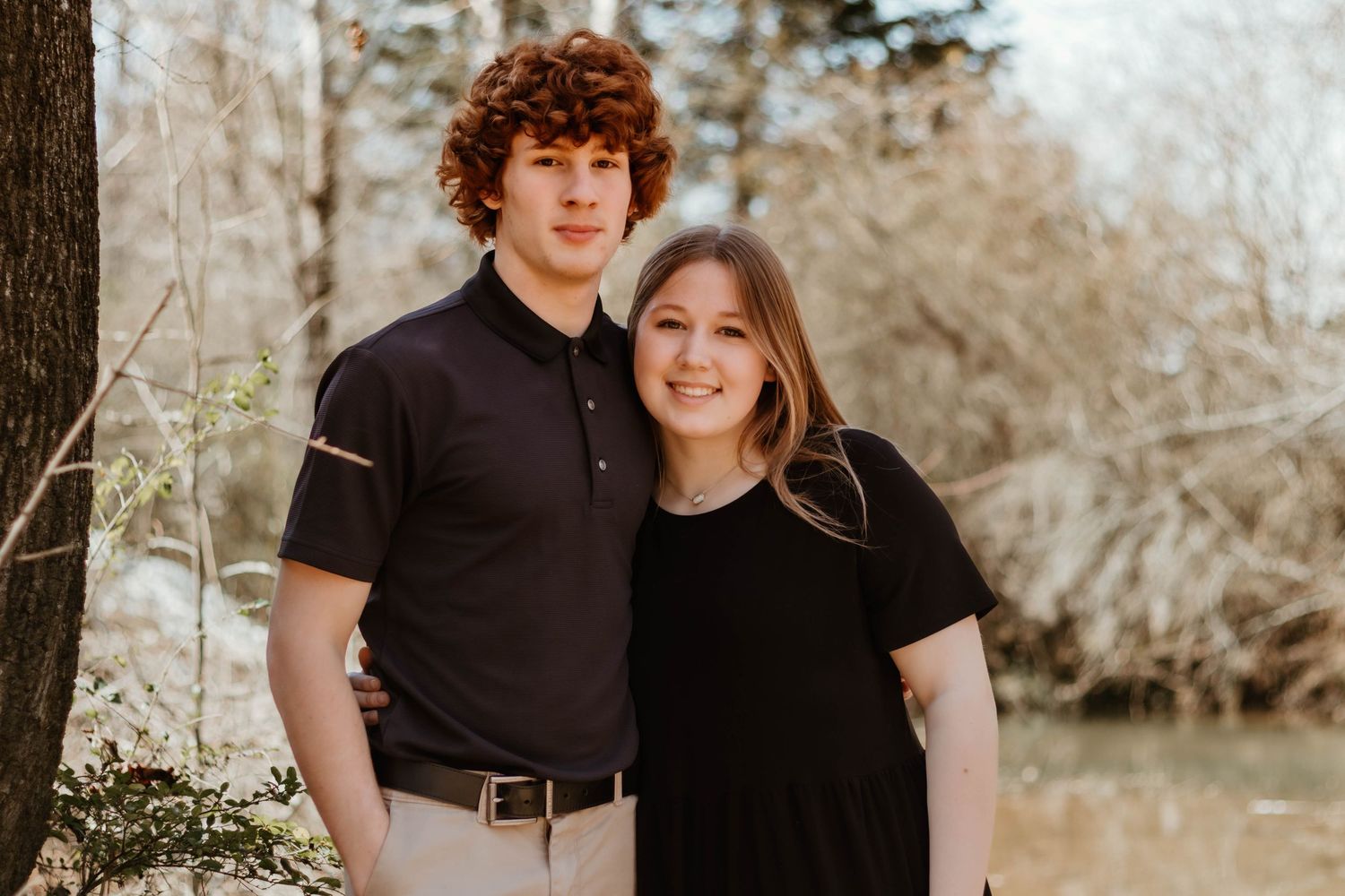 A happy couple in matching black tops pose together for a portrait in a natural outdoor setting at Geary Farm.
