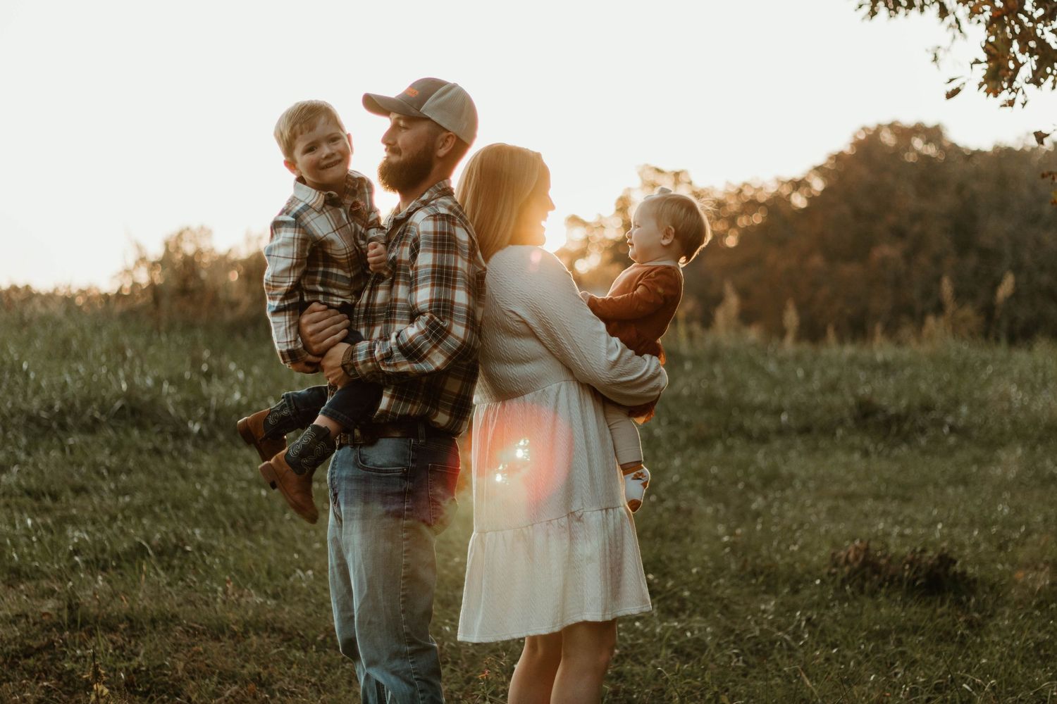 A family portrait session in a sunlit field during golden hour shows joyful moments together in Clarkesville, GA.